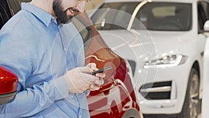 Cropped shot of a happy man using smart phone at car dealership