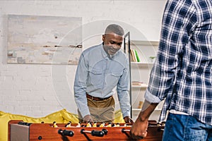 cropped shot of happy senior father and adult son playing table football