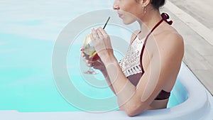 Cropped shot of a happy woman smiling drinking cocktail in the swimming pool