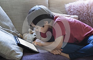 Cropped shot kid sitting on sofa watching cartoons on tablet,6-7 year old boy playing game on touch pad, Cute Kid having fun and
