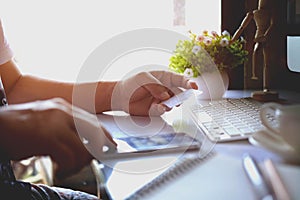 Cropped shot of male hands holding smart phone with blank screen for online shopping over the desk.