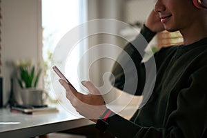 Cropped shot of man chatting online, typing text message to his friends via smart phone