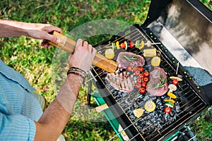 cropped shot of man with grinder cooking food on grill during barbecue