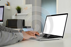 Cropped shot of man office worker hands typing on keyboard of computer laptop with white screen.