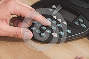 cropped shot of man pushing button of conference phone