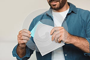 Cropped shot of man receiving letter, holding envelope at home