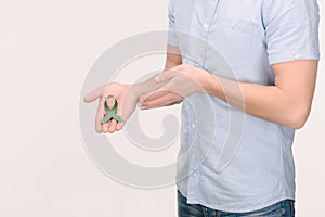 cropped shot of man showing green awareness ribbon for Adrenal Cancer, Aging research awareness, BiPolar Disorder