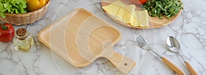 Cropped shot of marble kitchen table with kitchenware, cheese, vegetables, ingredients