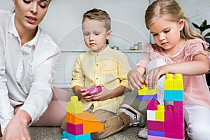 cropped shot of mother with cute little kids playing with colorful blocks