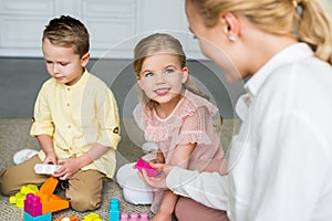 cropped shot of mother looking at cute little kids playing with colorful blocks