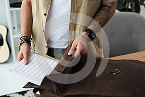 Musician putting music notebook into bag