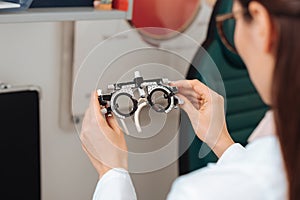 cropped shot of optometrist in white coat holding trial frame