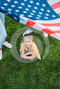 cropped shot of parents holding american flag and little son crouching