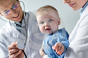 cropped shot of pediatricians checking breath of adorable