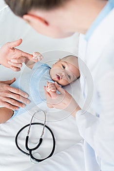 cropped shot of pediatricians playing with little baby photo