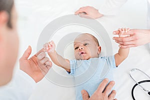 cropped shot of pediatricians tickling adorable little baby photo