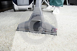 cropped shot of person cleaning white carpet with professional vacuum