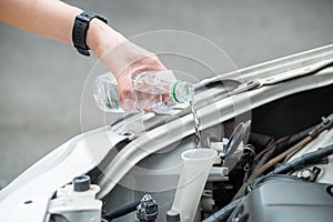 Cropped shot of person hand filling water into car radiator for reduce engine overheating.