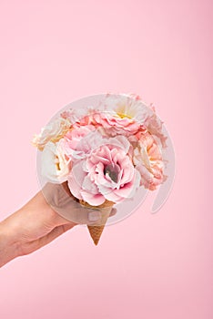Cropped shot of person holding waffle cone with beautiful blooming flowers