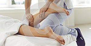 Physiotherapist, reflexologist or professional masseur massaging woman& x27;s calf in wellness center photo