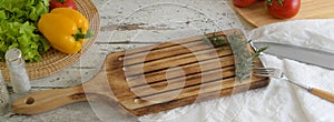 Cropped shot of plank kitchen table with kitchenware, dish towel, vegetables and ingredients