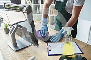 cropped shot of professional cleaner in rubber gloves cleaning computer keyboard