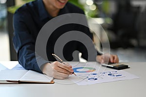 Cropped shot professional economist using calculator and checking financial reports on white office desk