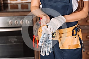 cropped shot of repairwoman putting on work gloves