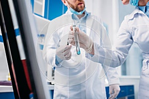 cropped shot of scientists in white coats with tube