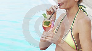 Cropped shot of a sexy woman in a bikini sipping cocktail near the pool