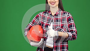 Cropped shot of a smiling female engineer showing thimbs up holding hardhat