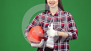 Cropped shot of a smiling female engineer showing thimbs up holding hardhat