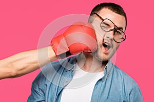 cropped shot of someone in boxing glove hitting man in eyeglasses isolated