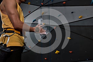 Cropped shot of sportive man applying white dust of magnesia, chalk on hands before climbing wall in bouldering center