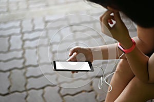 Cropped shot sporty woman holding empty screen smartphone with ear phone.