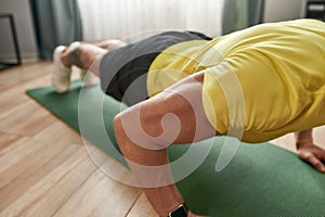 Cropped shot of a strong man fitness instructor in sportswear doing push ups on yoga mat at home