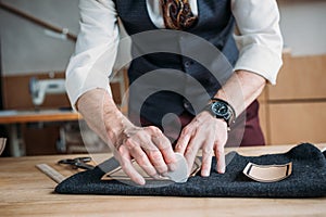 cropped shot of stylish tailor marking cloth pattern with chalk