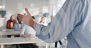 Cropped shot of teacher gesturing hands while giving lecture to students in classroom