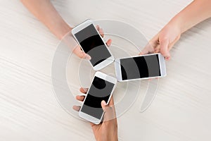 cropped shot of teenagers holding smartphones with blank screens