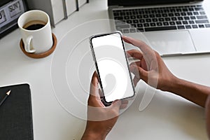 Cropped shot top view of businessman hands using smartphone mockup on office desk. Blank screen mobile phone for graphic display