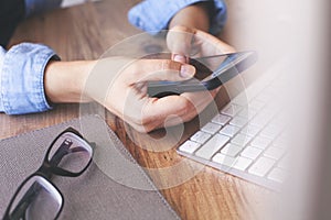 Cropped shot top view of businesswoman hands using smartphone mockup at the wooden office desk. Blank screen mobile phone for grap