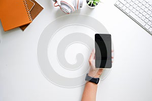 Cropped shot top view of  hands using smartphone mockup at the white office desk. Blank screen mobile phone