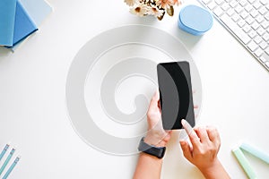 Cropped shot top view of women hands using smartphone mockup at the white office desk. mobile phone