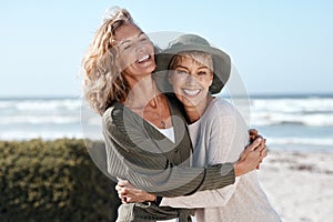 Best friends for life. Cropped shot of two attractive mature women hugging while standing on the beach.