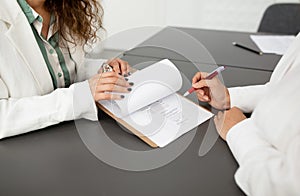 Cropped shot of two businesswomen signing business paper at office