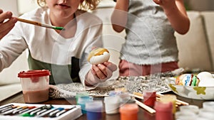 Cropped shot of two little children, brother and sister painting colorful Easter eggs while spending time together at