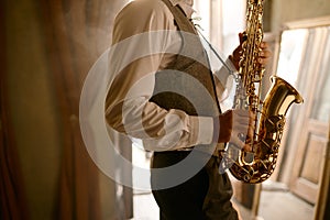 Cropped shot of unrecognizable male musician playing his saxophone at home