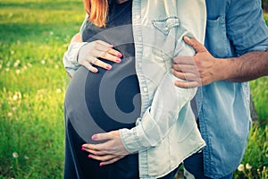 Cropped shot view of expecting parents hugging and holding belly. Pregnancy, maternity and new family concept.