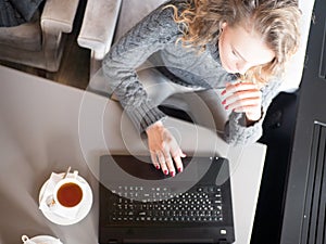 Cropped shot view of a woman keyboarding on laptop, young female person working on net-book while sitting in coffee shop