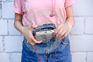 cropped shot of woman with earphones holding retro cassette player in hands against white